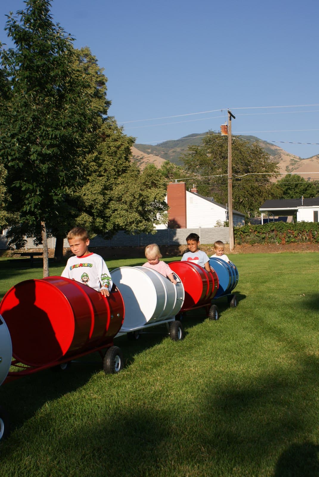 Kids riding the Backyard Barrel Express with mountains behind